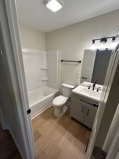 full bathroom with vanity, wood-type flooring, tub / shower combination, and toilet