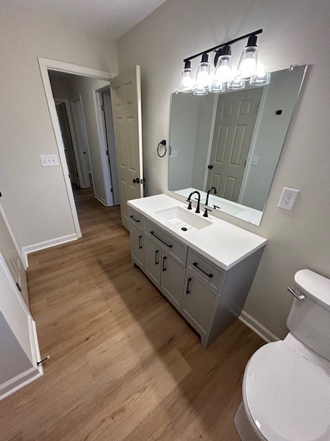 bathroom with an inviting chandelier, vanity, wood-type flooring, and toilet