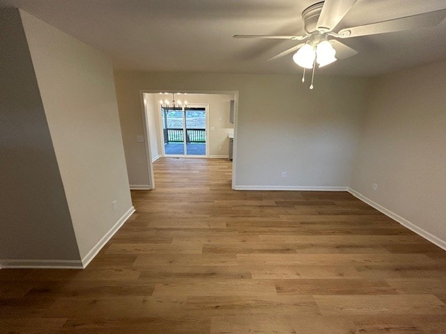 empty room with ceiling fan with notable chandelier and hardwood / wood-style flooring