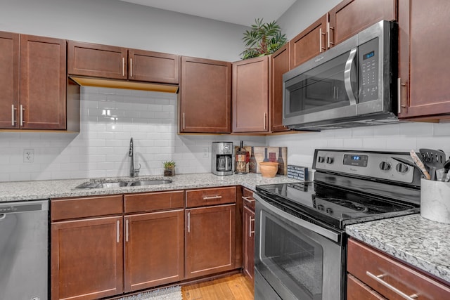 kitchen with light stone counters, sink, light hardwood / wood-style floors, and appliances with stainless steel finishes