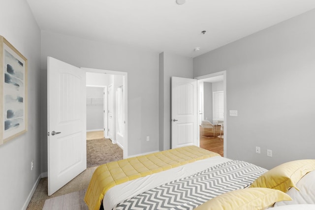 bedroom with a walk in closet, baseboards, a closet, and carpet flooring