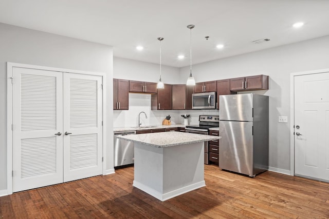 kitchen with dark brown cabinetry, appliances with stainless steel finishes, wood finished floors, and a sink