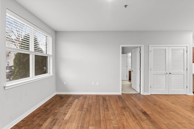 unfurnished bedroom featuring a closet, baseboards, and hardwood / wood-style floors