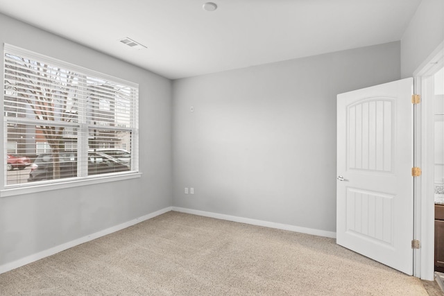 empty room featuring light carpet, visible vents, and baseboards