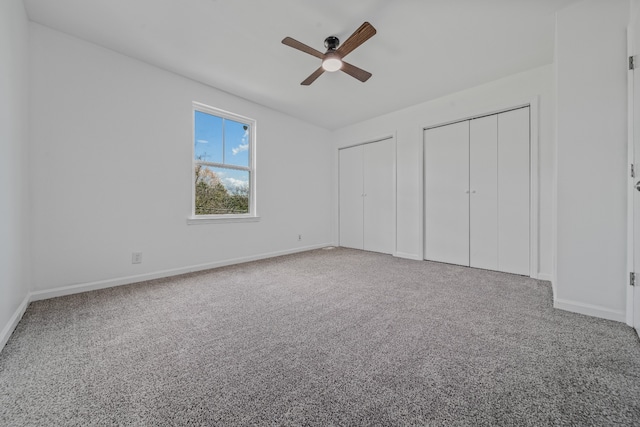 unfurnished bedroom featuring ceiling fan, carpet floors, and two closets