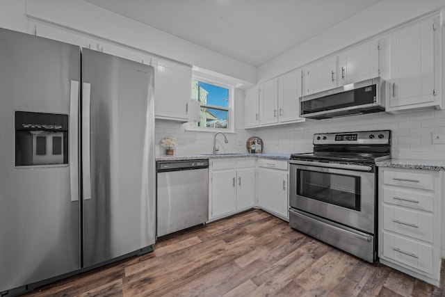 kitchen featuring white cabinetry, sink, dark wood-type flooring, stainless steel appliances, and light stone counters