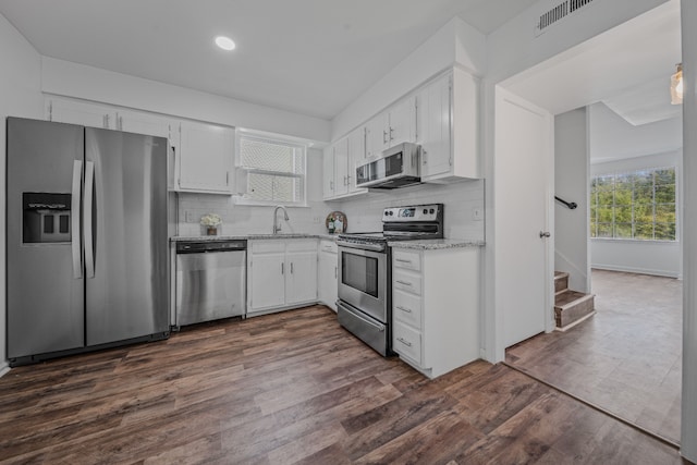 kitchen featuring dark hardwood / wood-style flooring, backsplash, stainless steel appliances, and white cabinetry