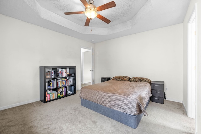 carpeted bedroom with ceiling fan, a raised ceiling, and a textured ceiling