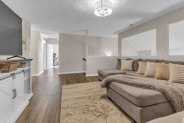 living room featuring wood-type flooring, a textured ceiling, and a notable chandelier