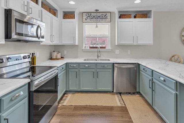 kitchen featuring white cabinetry, sink, stainless steel appliances, light stone counters, and light wood-type flooring