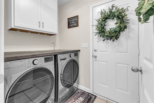 laundry room featuring washer and dryer, cabinets, and light tile patterned floors