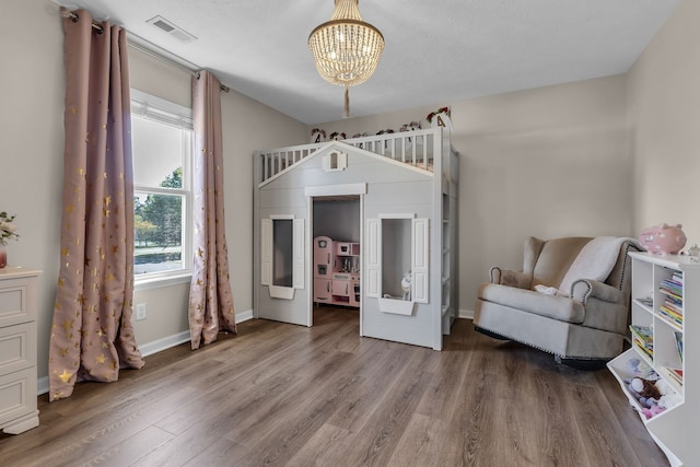 bedroom with a textured ceiling, a notable chandelier, and hardwood / wood-style flooring