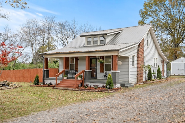 bungalow-style home with covered porch, an outbuilding, and a front lawn