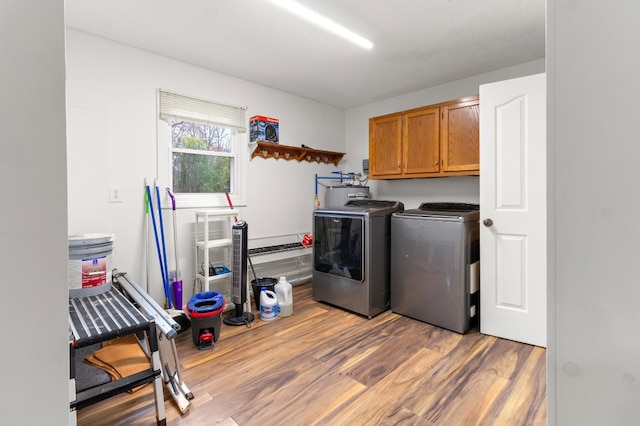 laundry room with separate washer and dryer, hardwood / wood-style floors, and cabinets