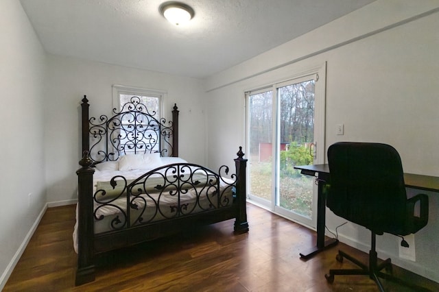 bedroom with access to exterior, dark hardwood / wood-style floors, and multiple windows