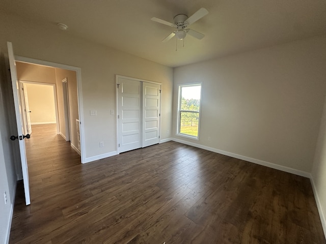 unfurnished bedroom with ceiling fan, dark wood-type flooring, and a closet