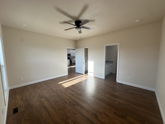 unfurnished bedroom with ensuite bath, ceiling fan, and dark wood-type flooring