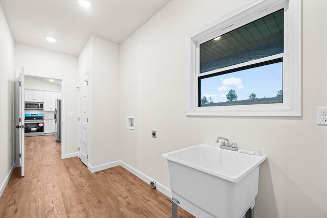 clothes washing area with hookup for an electric dryer, light wood-type flooring, sink, and washer hookup