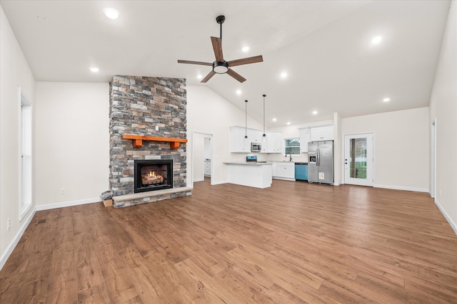 unfurnished living room with a fireplace, light wood-type flooring, ceiling fan, and lofted ceiling