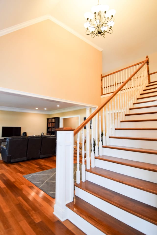 staircase featuring ornamental molding, a notable chandelier, and hardwood / wood-style flooring