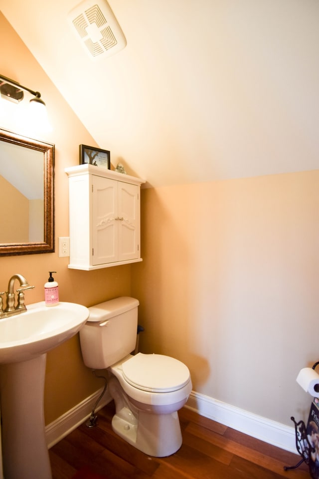 bathroom featuring toilet, sink, vaulted ceiling, and hardwood / wood-style floors