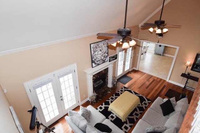 living room featuring french doors, ceiling fan, hardwood / wood-style flooring, ornamental molding, and a high end fireplace