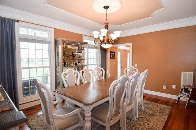 dining space with dark wood-type flooring, ornamental molding, and a chandelier