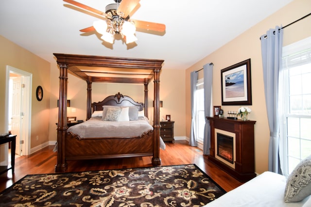 bedroom with ceiling fan, dark hardwood / wood-style flooring, and multiple windows