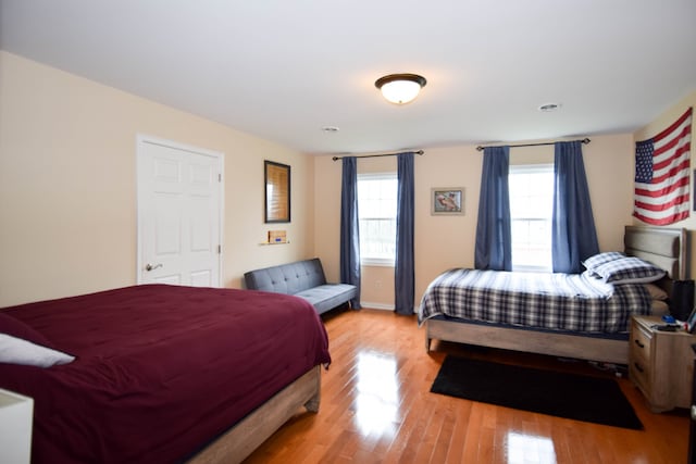 bedroom with light hardwood / wood-style floors and multiple windows