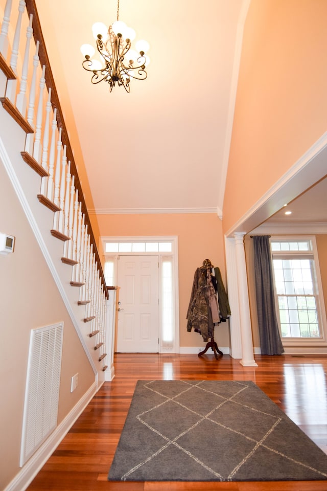 foyer entrance with ornamental molding, dark hardwood / wood-style flooring, a notable chandelier, and a towering ceiling