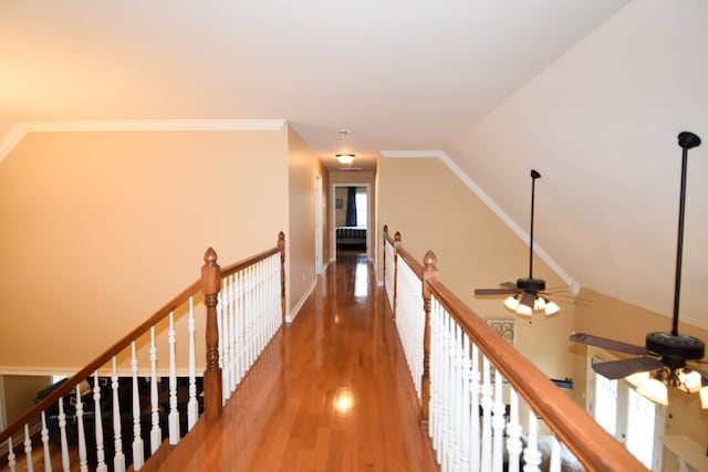 corridor with hardwood / wood-style flooring, vaulted ceiling, and crown molding