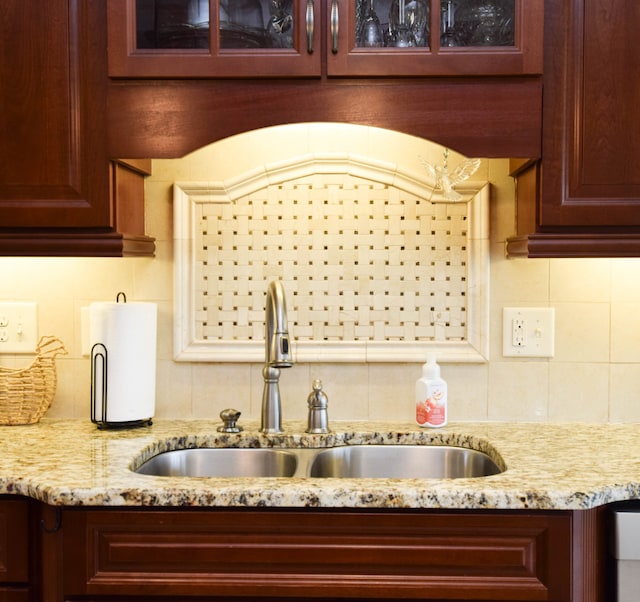 room details featuring sink, light stone countertops, and decorative backsplash