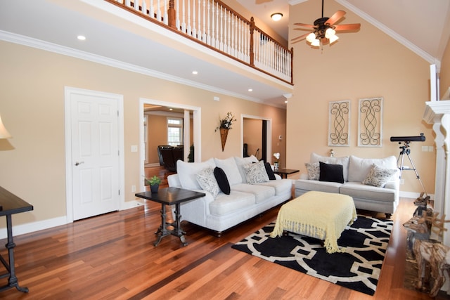 living room with a high ceiling, ceiling fan, ornamental molding, and dark hardwood / wood-style floors