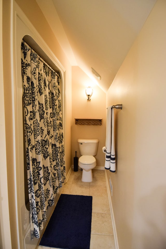 bathroom featuring tile patterned flooring, vaulted ceiling, and toilet