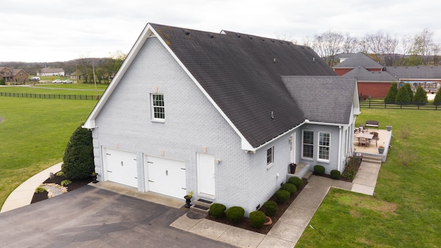 exterior space featuring a garage, a yard, and a patio area