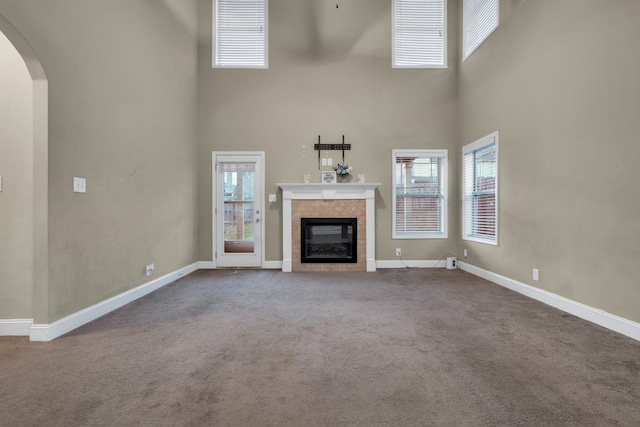 unfurnished living room featuring carpet, a fireplace, and a towering ceiling