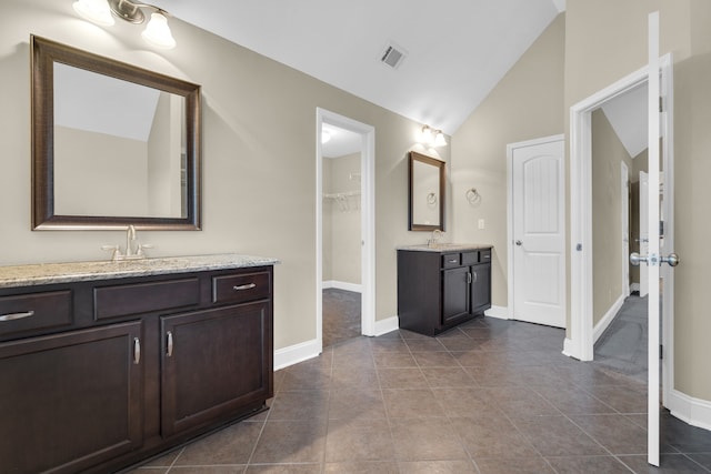 bathroom with tile patterned flooring, vanity, and vaulted ceiling