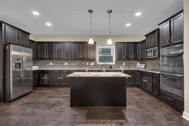 kitchen featuring decorative backsplash, dark brown cabinets, stainless steel appliances, a center island, and hanging light fixtures