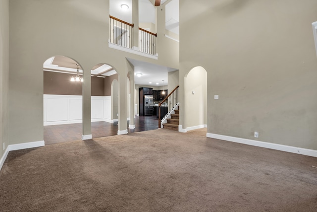 unfurnished living room with dark colored carpet and a towering ceiling