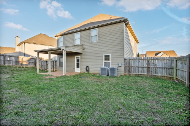 back of property with a lawn, central air condition unit, and a patio