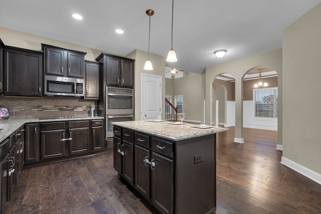 kitchen featuring a center island, tasteful backsplash, dark hardwood / wood-style flooring, decorative light fixtures, and appliances with stainless steel finishes