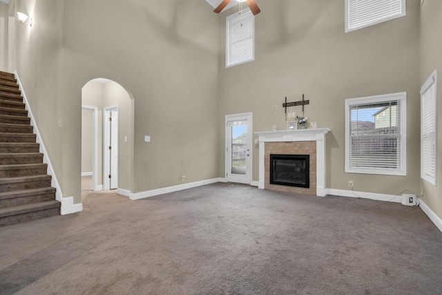 unfurnished living room with ceiling fan and a high ceiling