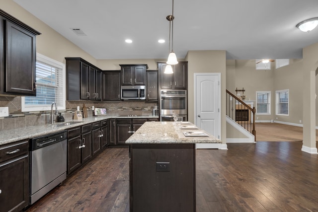 kitchen featuring pendant lighting, sink, dark hardwood / wood-style floors, appliances with stainless steel finishes, and a kitchen island