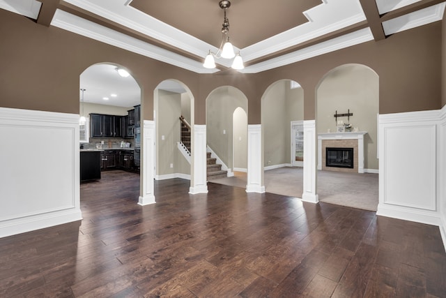 unfurnished living room featuring dark hardwood / wood-style flooring, coffered ceiling, crown molding, a tile fireplace, and beam ceiling