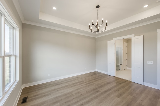 spare room featuring an inviting chandelier, a healthy amount of sunlight, and wood-type flooring