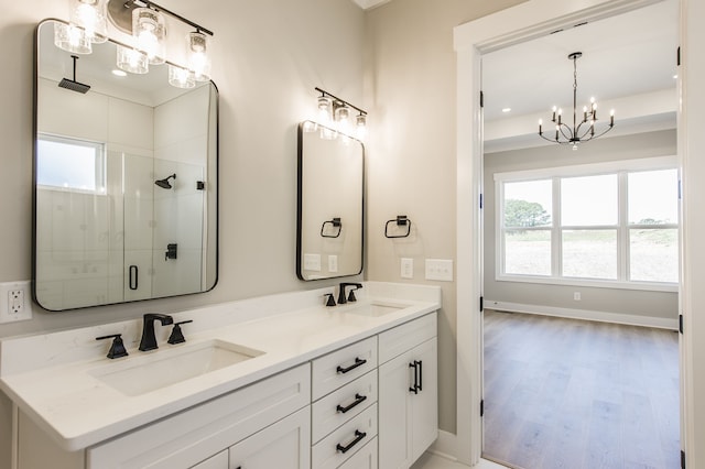 bathroom with a chandelier, hardwood / wood-style floors, vanity, and a shower with door