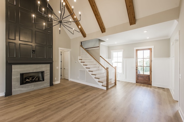 unfurnished living room with hardwood / wood-style floors, vaulted ceiling with beams, and a notable chandelier