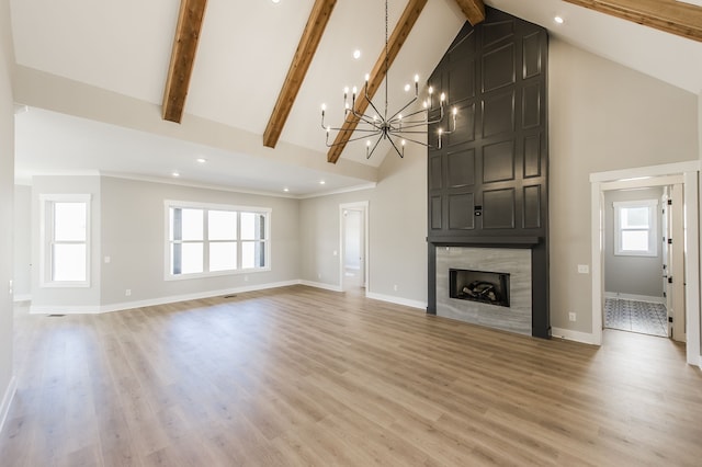 unfurnished living room with beam ceiling, high vaulted ceiling, an inviting chandelier, a fireplace, and hardwood / wood-style floors