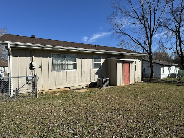 back of property with a yard and central AC