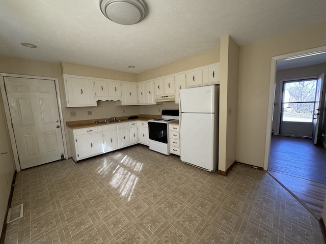 kitchen with white cabinets, a textured ceiling, white appliances, and sink